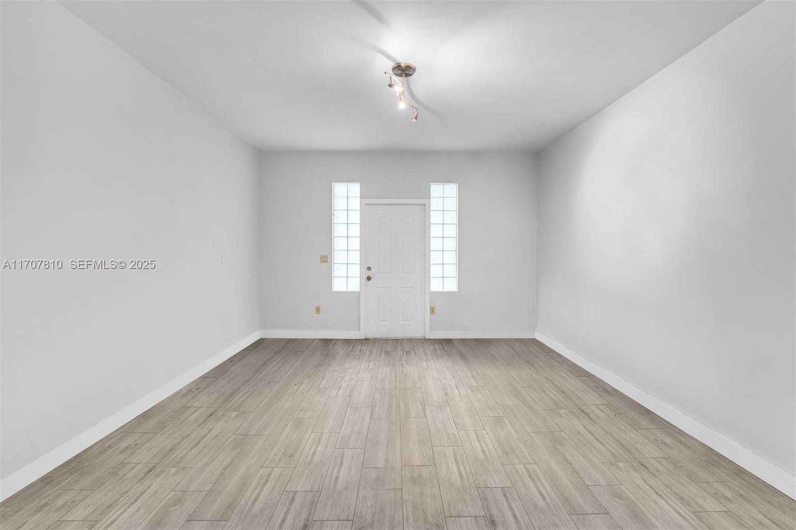 1622 Bay Road Miami Beach, FL 33139 - Photo 12 of 24 an empty room with wooden floor and windows