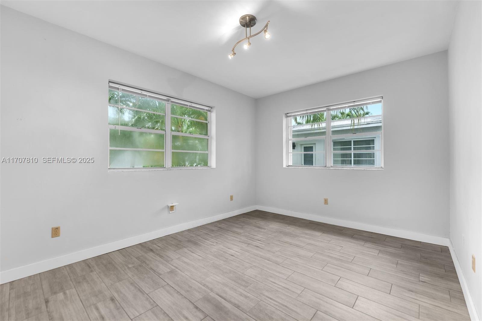1622 Bay Road Miami Beach, FL 33139 - Photo 14 of 24 a view of an empty room with wooden floor and a window