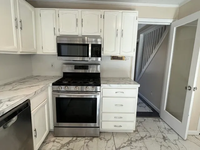 a kitchen with granite countertop white cabinets and stainless steel appliances