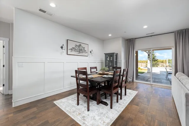 a kitchen with stainless steel appliances a dining table chairs stove refrigerator and cabinets