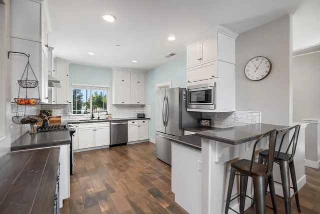 a kitchen with granite countertop white cabinets white appliances a sink and a large window