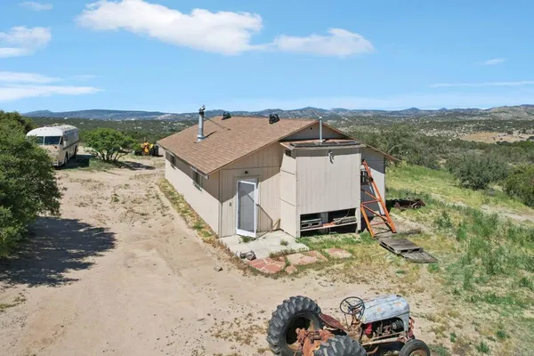 an aerial view of a house with a yard and mountain view in back