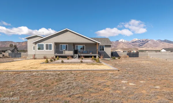 a front view of a house with a dirt yard and a large tree