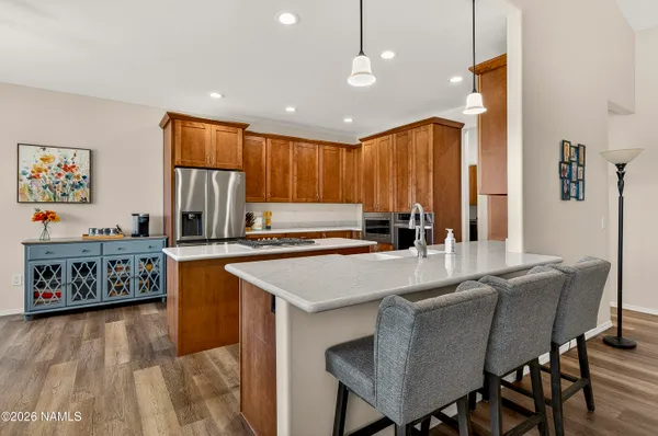 a kitchen with stainless steel appliances granite countertop a table chairs sink and window