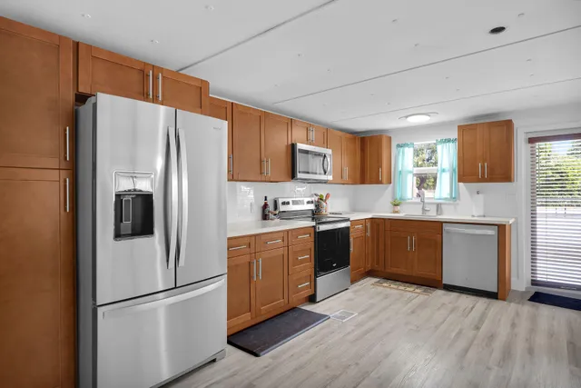 a kitchen with stainless steel appliances granite countertop a stove top oven a refrigerator a dining table and chairs with wooden floor