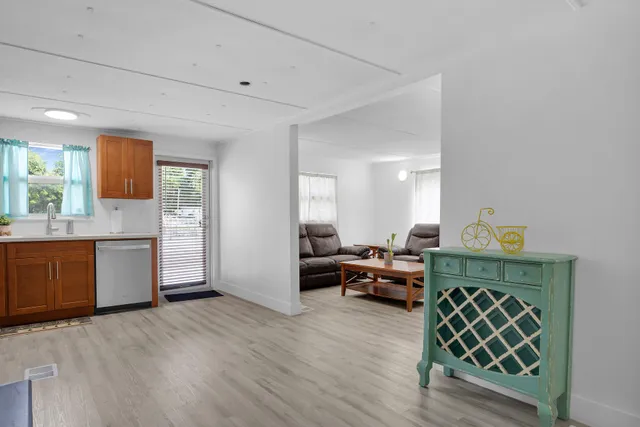 a living room with furniture kitchen view and a window