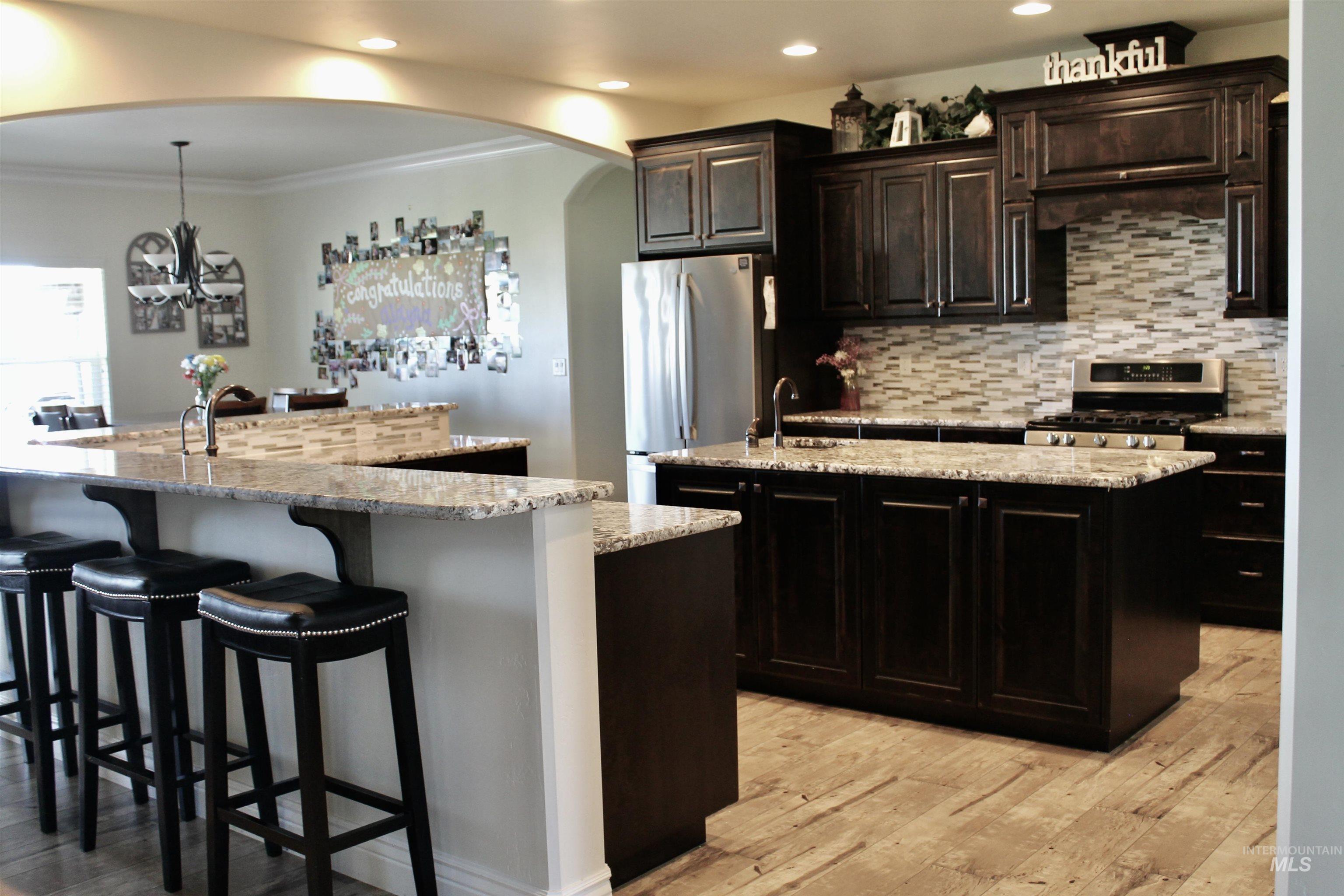 2464 Windmill Drive Twin Falls, ID 83301 - Photo 14 of 47 Kitchen featuring an island with sink, freestanding refrigerator, recessed lighting, light wood-type flooring, and a breakfast bar