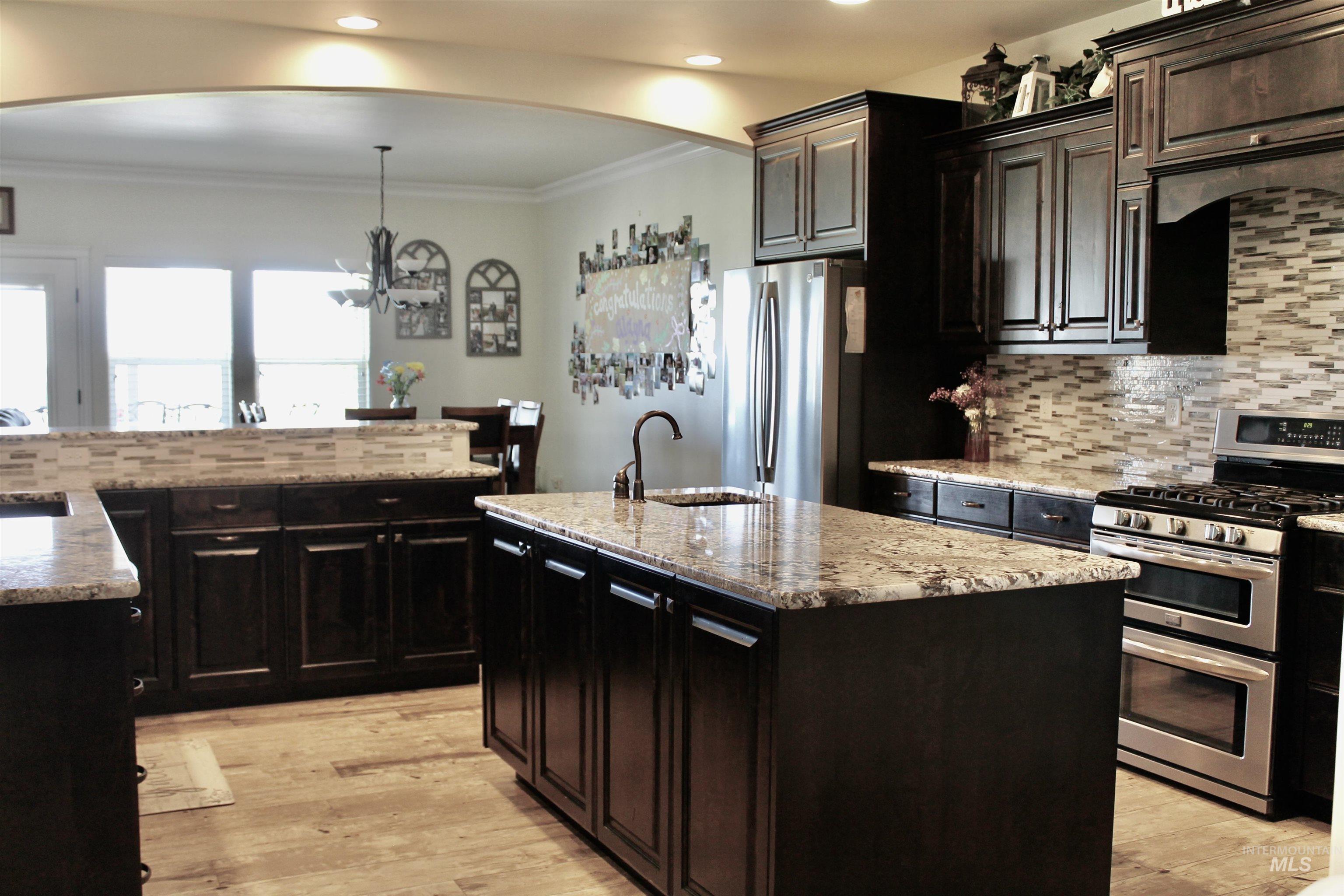 2464 Windmill Drive Twin Falls, ID 83301 - Photo 15 of 47 Kitchen with tasteful backsplash, appliances with stainless steel finishes, a chandelier, an island with sink, and arched walkways