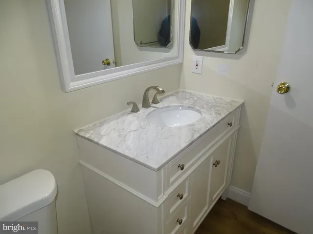 a bathroom with a granite countertop sink and a toilet