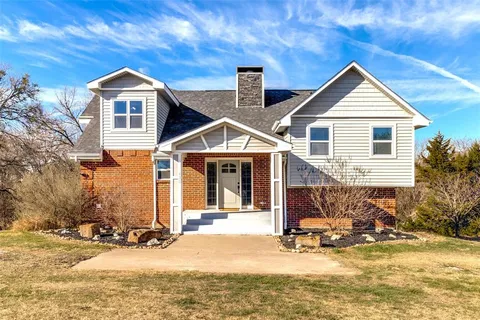 a view of a house with a yard chairs and floor to ceiling window
