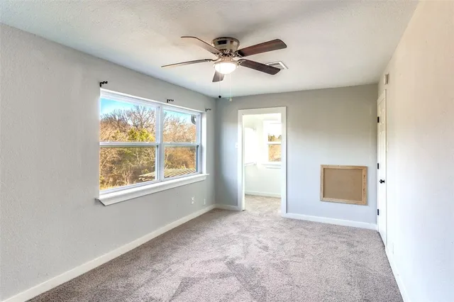 an empty room with a ceiling fan and a window