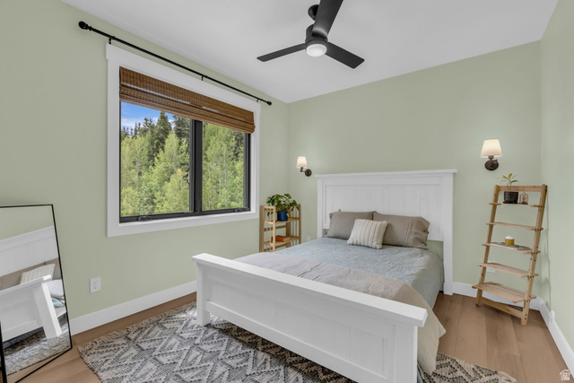 1766 West Tollgate Cyn Road Coalville, UT 84017 - Photo 33 of 59 Bedroom featuring a large picture window, wood-finish flooring, ceiling fan, and wall sconces