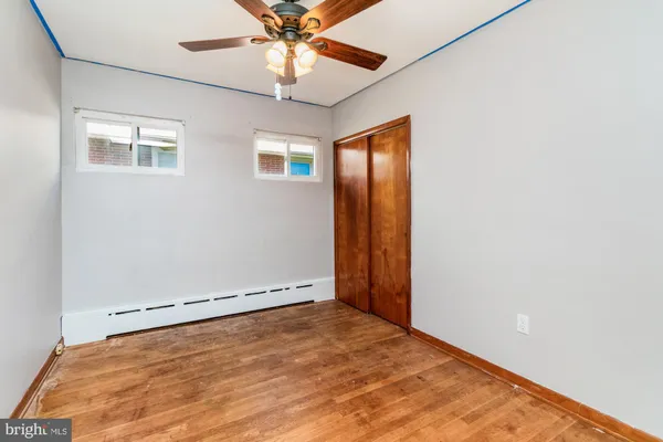 an empty room with a chandelier fan and windows