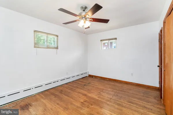 an empty room with wooden floor and ceiling fan
