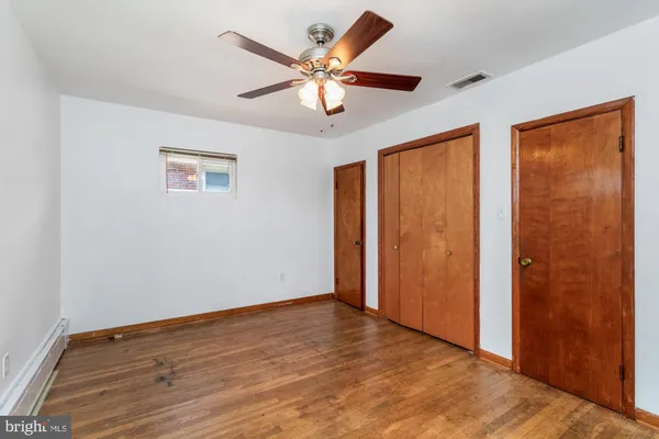 a view of an empty room with wooden floor and a ceiling fan