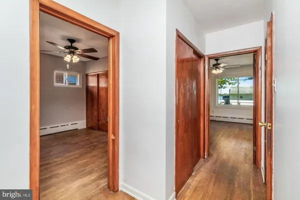 a view of a hallway with wooden floor and a ceiling fan