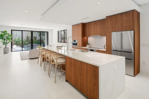 a kitchen with stainless steel appliances a microwave a stove a refrigerator a sink dishwasher with a dining table and chairs with wooden floor