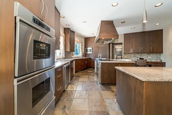 a kitchen with stainless steel appliances granite countertop a refrigerator a stove and a sink