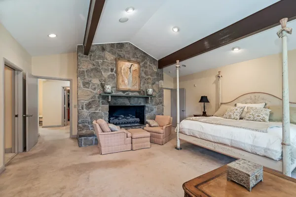 a spacious bedroom with a bed a fireplace and a couch