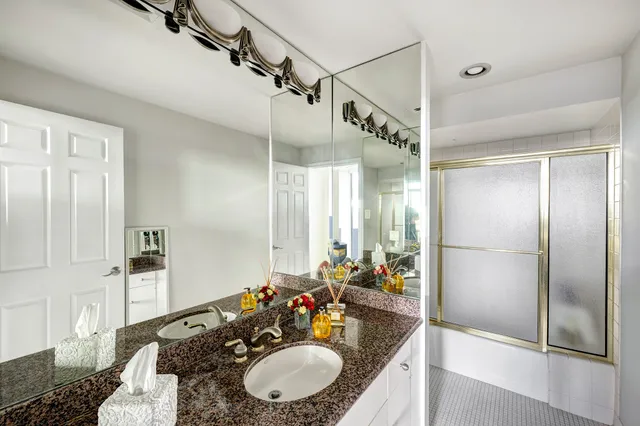 a bathroom with a granite countertop sink a mirror and a shower