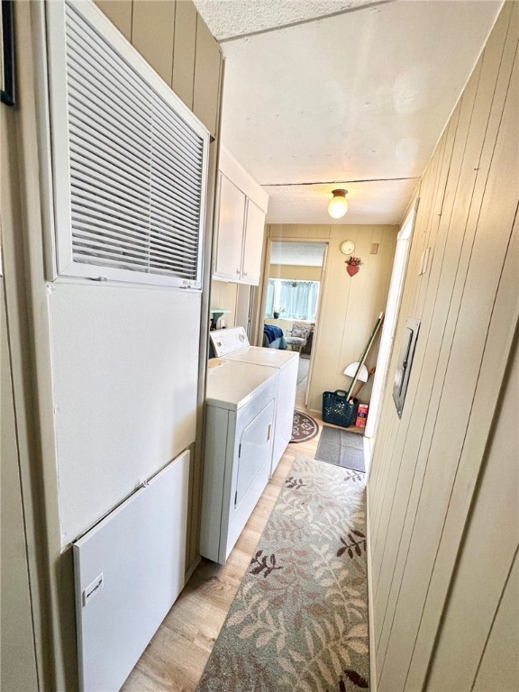 3309 Bacobi Road Golden Valley, AZ 86413 - Photo 21 of 31 Laundry room featuring cabinet space, a heating unit, wooden walls, washing machine and dryer, and light wood-style floors