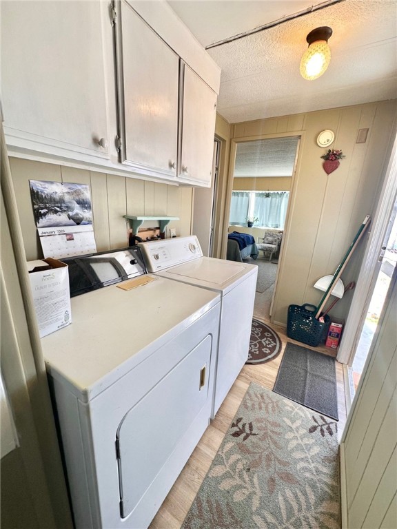 3309 Bacobi Road Golden Valley, AZ 86413 - Photo 22 of 31 Washroom featuring light wood-style flooring, cabinet space, washing machine and dryer, and wood walls