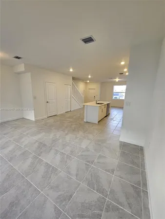 a view of a kitchen with kitchen island granite countertop a large counter top stainless steel appliances and cabinets