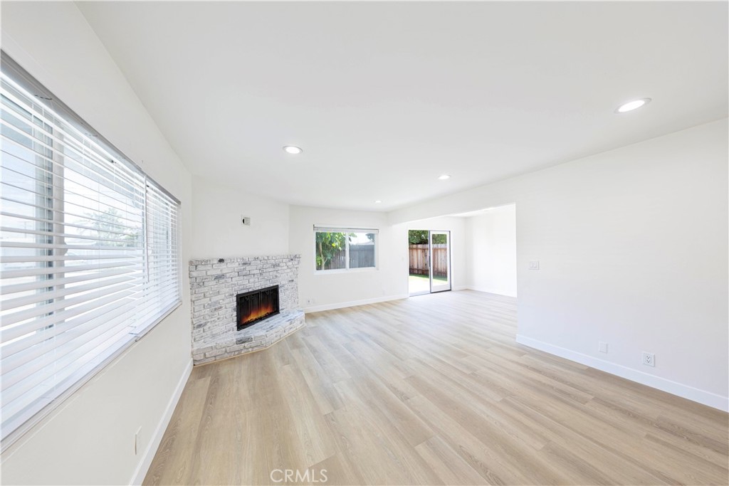 a view of empty room with fireplace and wooden floor