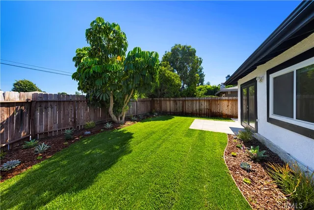 a view of a backyard with large tree and wooden fence