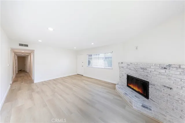 an empty room with wooden floor fireplace and cabinet