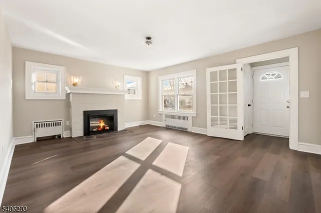 an empty room with wooden floor fireplace and windows