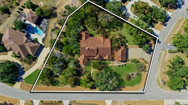 an aerial view of residential houses with outdoor space and trees