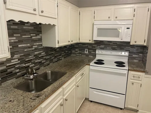 a kitchen with granite countertop white cabinets and white appliances