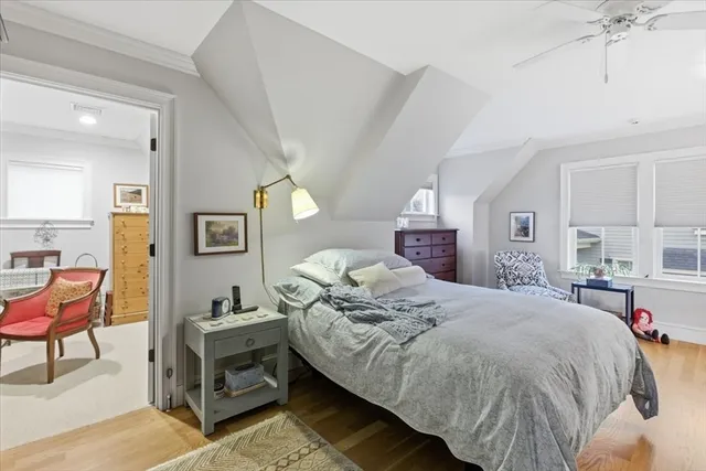 a bedroom with a bed a chair and potted plant on the dresser
