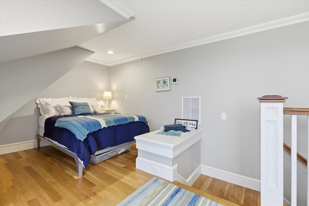 1090 Shore Road, Unit 7 Bourne, MA 02559 - Photo 34 of 42 a bedroom with a bed and wooden floor