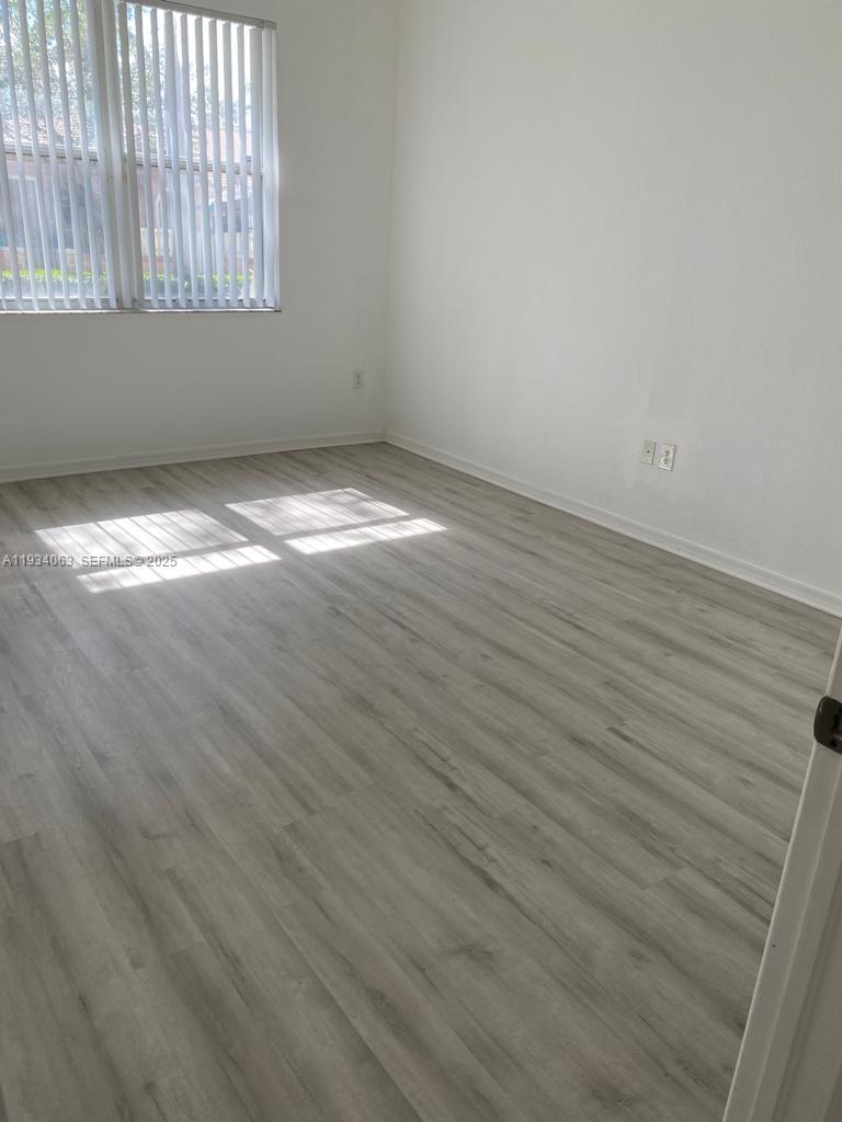 11024 Southwest 237th Lane Homestead, FL 33032 - Photo 14 of 16 an empty room with wooden floor and windows