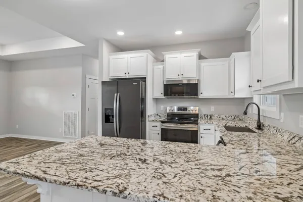 a kitchen with stainless steel appliances granite countertop a refrigerator stove microwave and sink