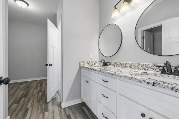 a bathroom with a granite countertop double vanity sink and a mirror