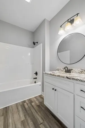 a bathroom with a granite countertop sink a mirror and bathtub