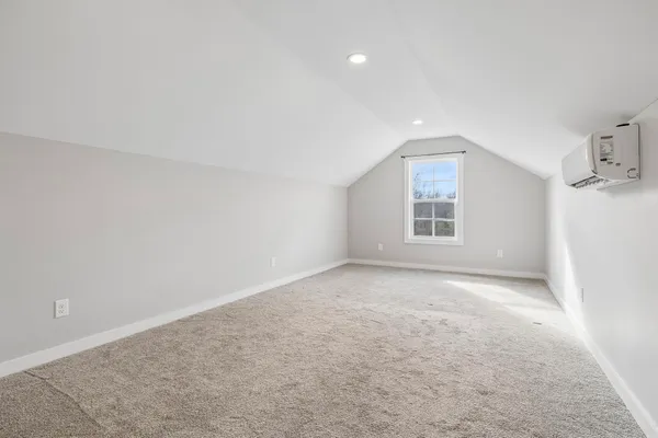 an empty room with windows and refrigerator