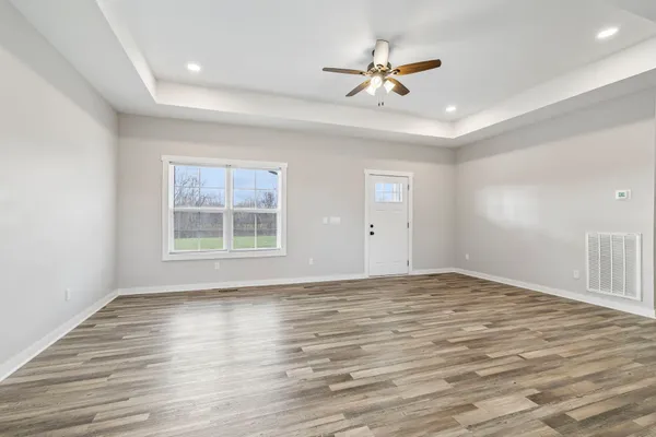 a view of an empty room with a window and wooden floor