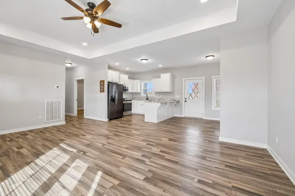 a view of an empty room with kitchen appliances and a ceiling fan