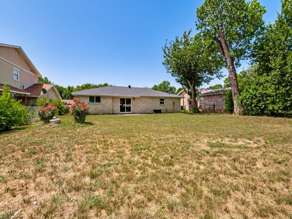1405 Rambler Road Arlington, TX 76014 - Photo 25 of 26 Expansive backyard featuring a brick exterior, mature trees, and a glass sliding door