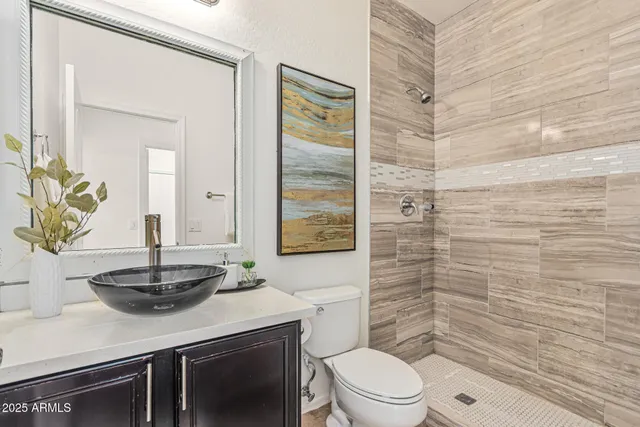 a bathroom with a granite countertop sink a toilet a mirror and shower