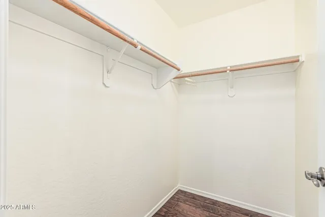 a view of an empty room with wooden floor and closet