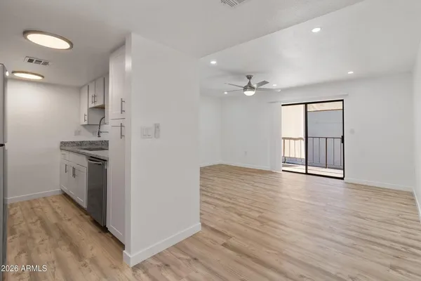 an empty room with wooden floor fan and windows