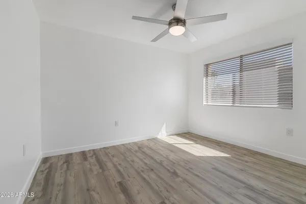 an empty room with wooden floor fan and windows