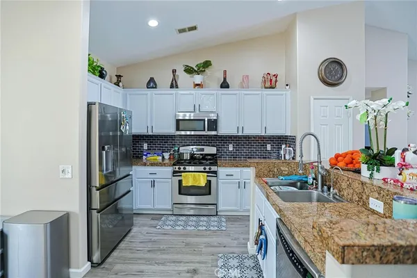 a kitchen with stainless steel appliances granite countertop a sink stove top oven and microwave