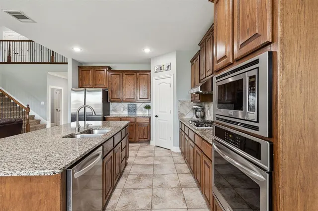 a kitchen with stainless steel appliances granite countertop a sink and stove top oven