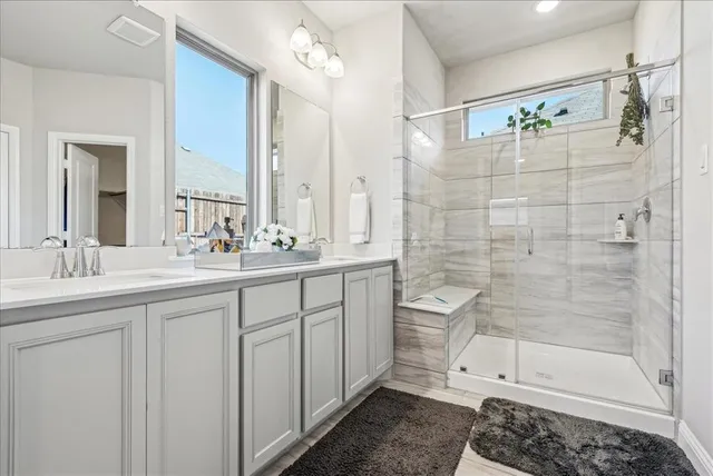 a bathroom with a double vanity sink a toilet and shower